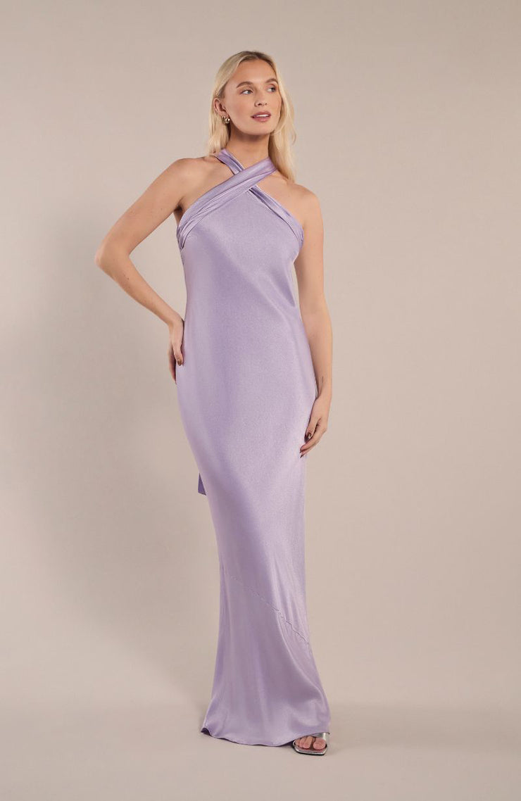 Woman wearing a lavender halterneck dress against a plain background