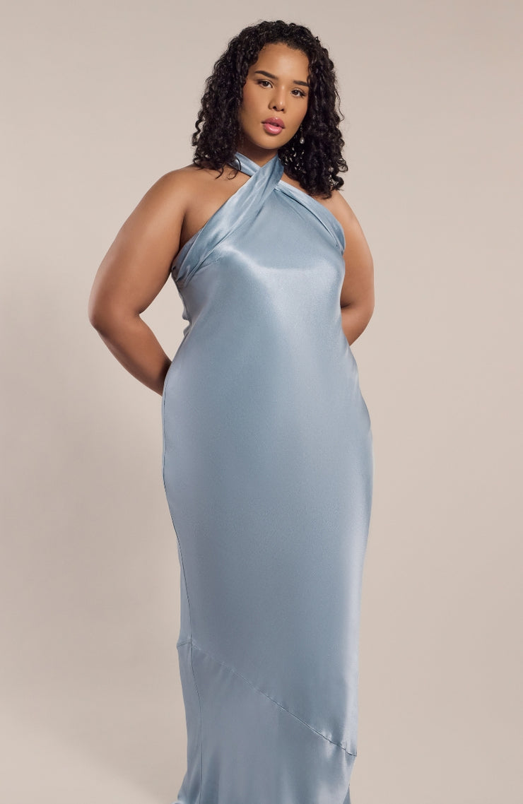 Woman wearing a light blue satin halter neck gown against a beige background