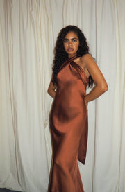 Woman wearing a brown satin dress against a white curtain background